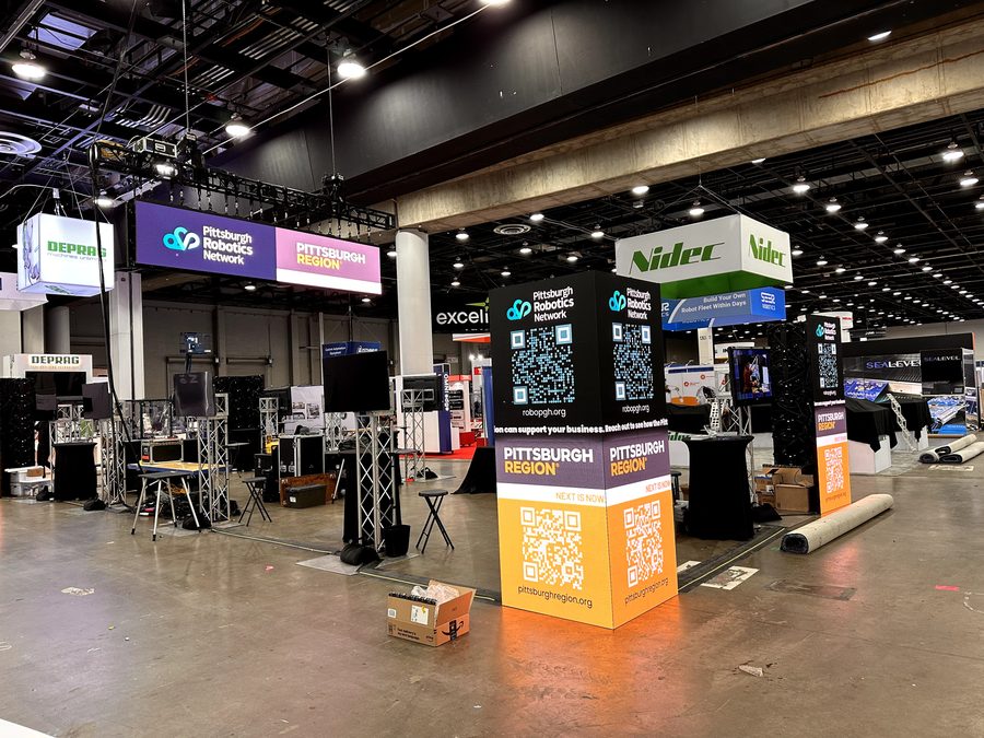 Pittsburgh Robotics Network branding across the booth during setup.