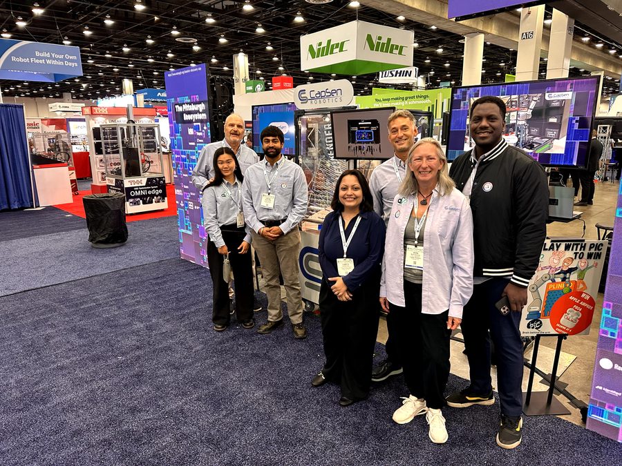 Group photo beside the robotics demonstration and animated display screens.