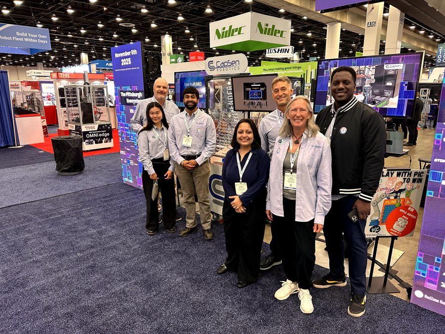 Group photo in the Pittsburgh Robotics Network booth, surrounded by the display graphics.